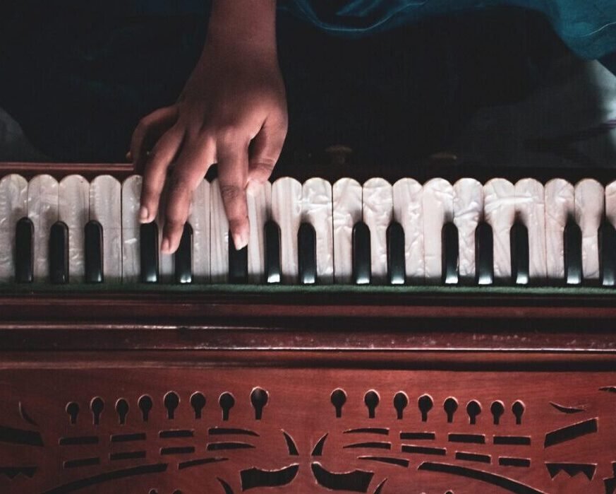 Someone plays a harmonium with hands on the keyboard