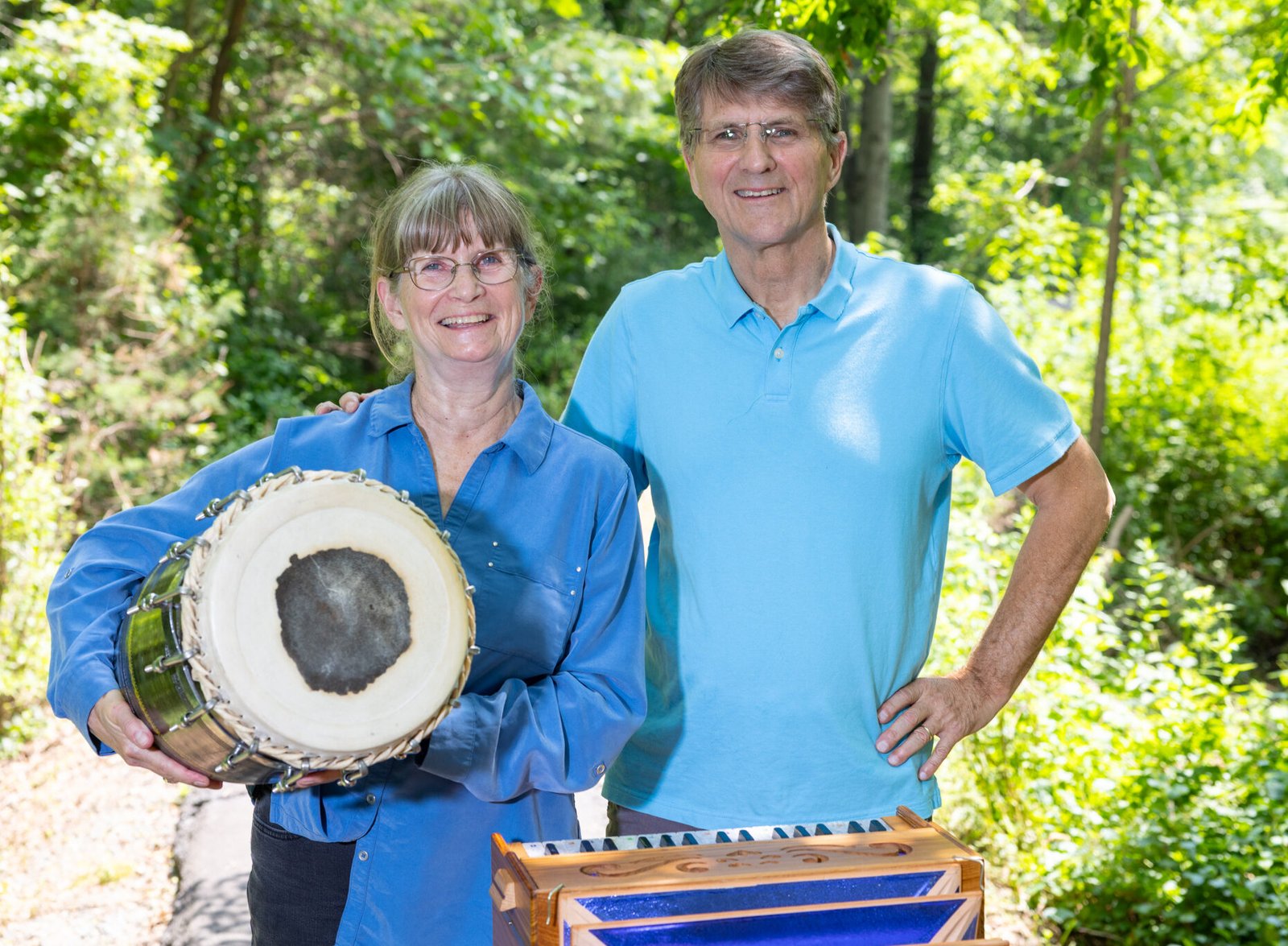 7E7A6384-3 Mukta Kiran members Martha and Geoff smile with their drum and harmonium.